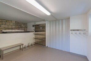 A clean, well-lit room with a stone wall, a bench, a wine rack, and a coat rack.