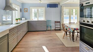 Eine Küche mit Holzboden, einem Esstisch mit Stühlen und einem großen Backofen.