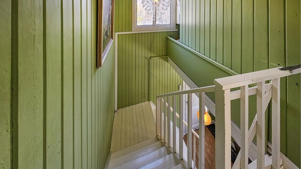 Una escalera con barandillas blancas y paredes verdes.