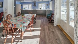 Ein geräumiger Essbereich mit einem langen Tisch, Holzstühlen und einer Tischdecke mit Muster.