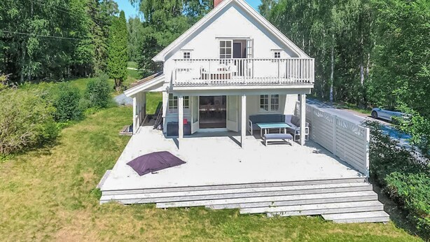 Ein zweistöckiges Haus mit Balkon, Veranda und kleiner Terrasse.