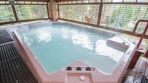 Un bain à remous doté d’une structure extérieure en pierre et d’une rambarde de sécurité en métal.
