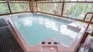 Un bain à remous doté d’une structure extérieure en pierre et d’une rambarde de sécurité en métal.