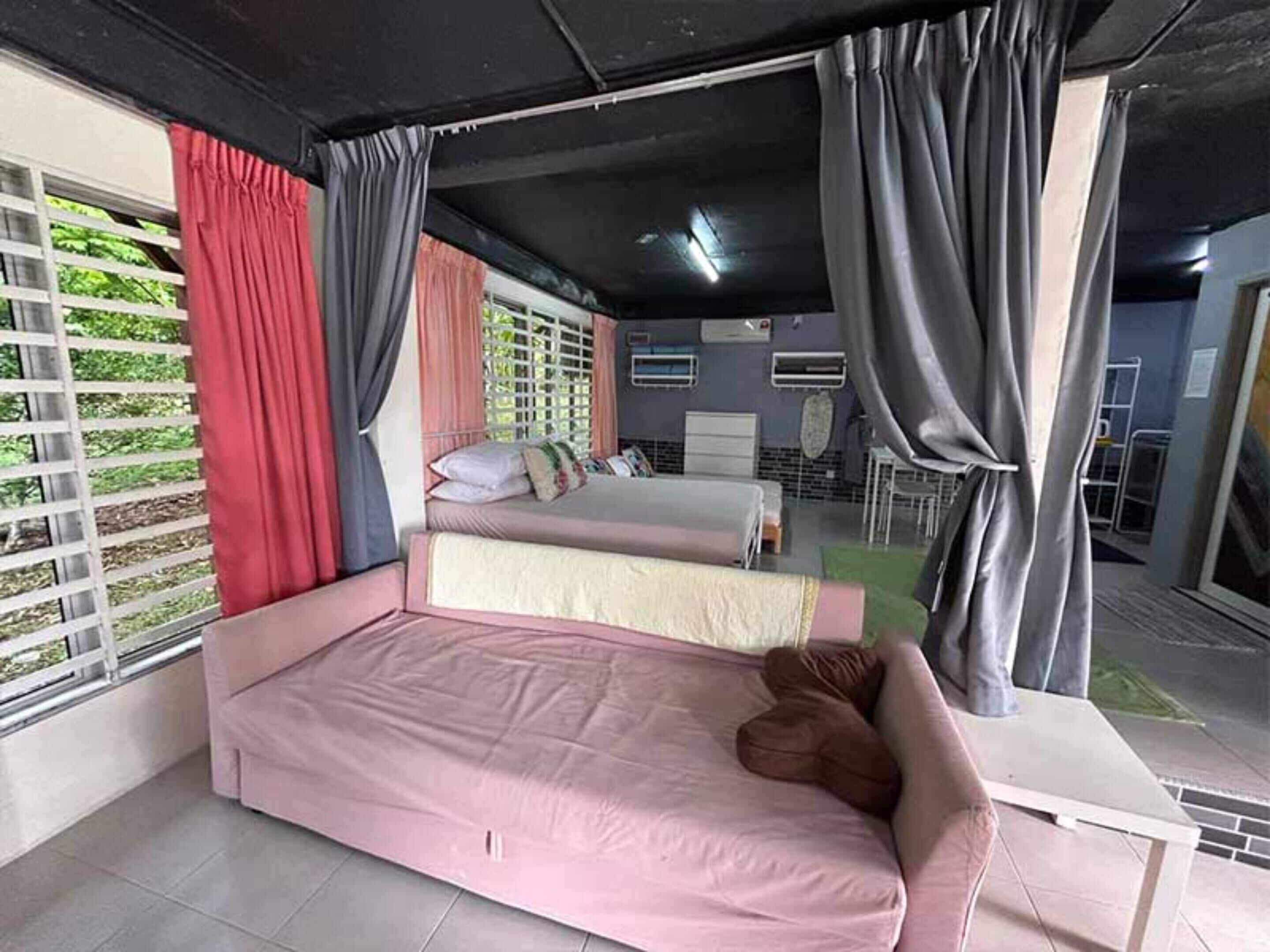 A bedroom with two beds, a desk, and a window with curtains.