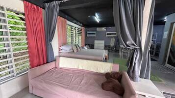 A bedroom with two beds, a desk, and a window with curtains.