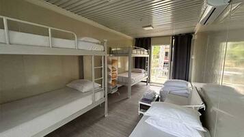 Une chambre avec deux lits superposés, un lit simple et une petite table avec une chaise.