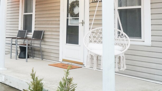 A house with a porch, a swing chair, and string lights. - The Laurelville in Hocking Hills Hills with Hot Tub (Laurelville)