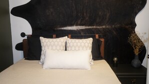 A bed with patterned pillows, a dark headboard, and a vase with dried plants on a bedside table. - The Laurelville in Hocking Hills Hills with Hot Tub (Laurelville)