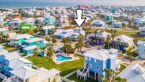 A coastal residential area with houses featuring a uniform architectural style, a central swimming pool, and a view of the ocean. - Beachside Bliss l Golf Cart + Pool Table! (Port Aransas)