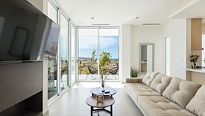 Una sala de estar moderna con un televisor grande, un sofá y un comedor con sillas.