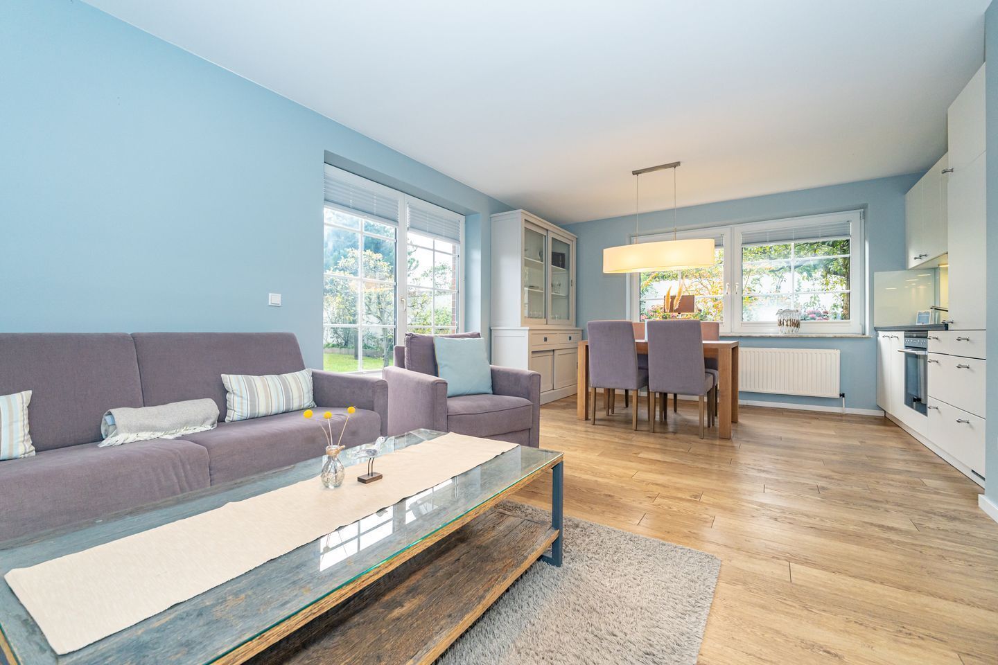 A modern living room with a sofa, coffee table, and dining area with chairs and a table.