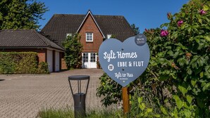A heart-shaped sign for Slyt Homes EBBE & FLUT with a house in the background. - Appartement Flut No. 5 - Appartement Flut 5 (Sylt)