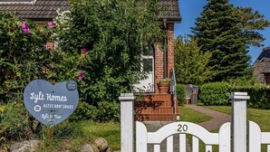 A residential property with a brick entrance, a garden with flowers, and a sign for Sylth Homes. - Appartement Hamburg, Deutschland (Westerland)