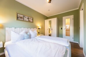 Un dormitorio ordenado con una cama grande, una mesita de noche, un armario y una lámpara fijada a la pared.