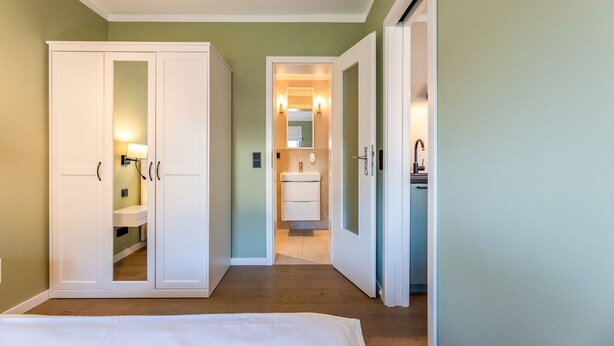 A hotel room with a wardrobe, a vanity with a mirror, and a sink. - Appartement Hamburg, Deutschland (Westerland)