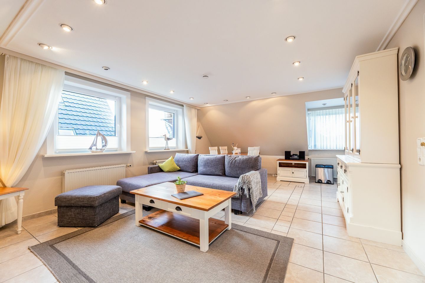 A modern living room with a sofa, a coffee table, and a dining area.