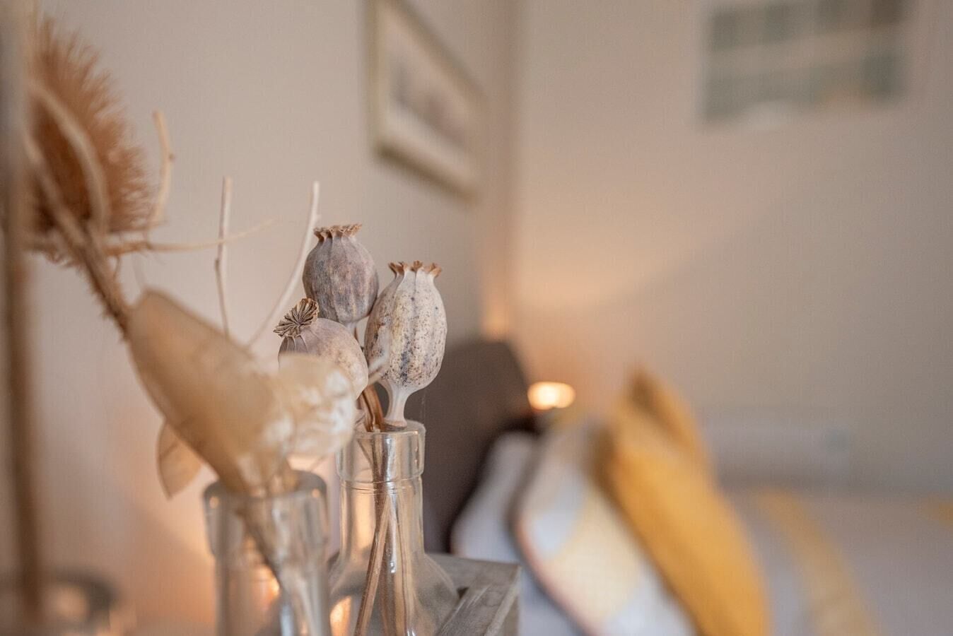 A vase with dried flowers and a feather on a table.