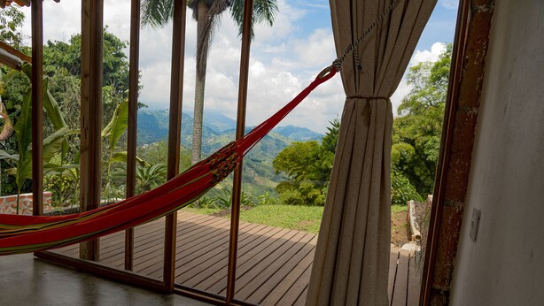 Una hamaca en una habitación con vista a montañas y vegetación.