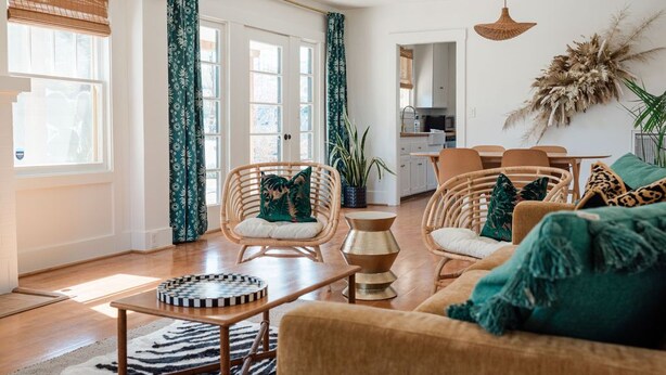 Een gezellige woonkamer met rieten meubels, een salontafel en een bank. Er is een eethoek met stoelen en een tafel.