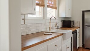 Een moderne keuken met witte kasten, een houten aanrecht, een roestvrijstalen koelkast en een magnetron.