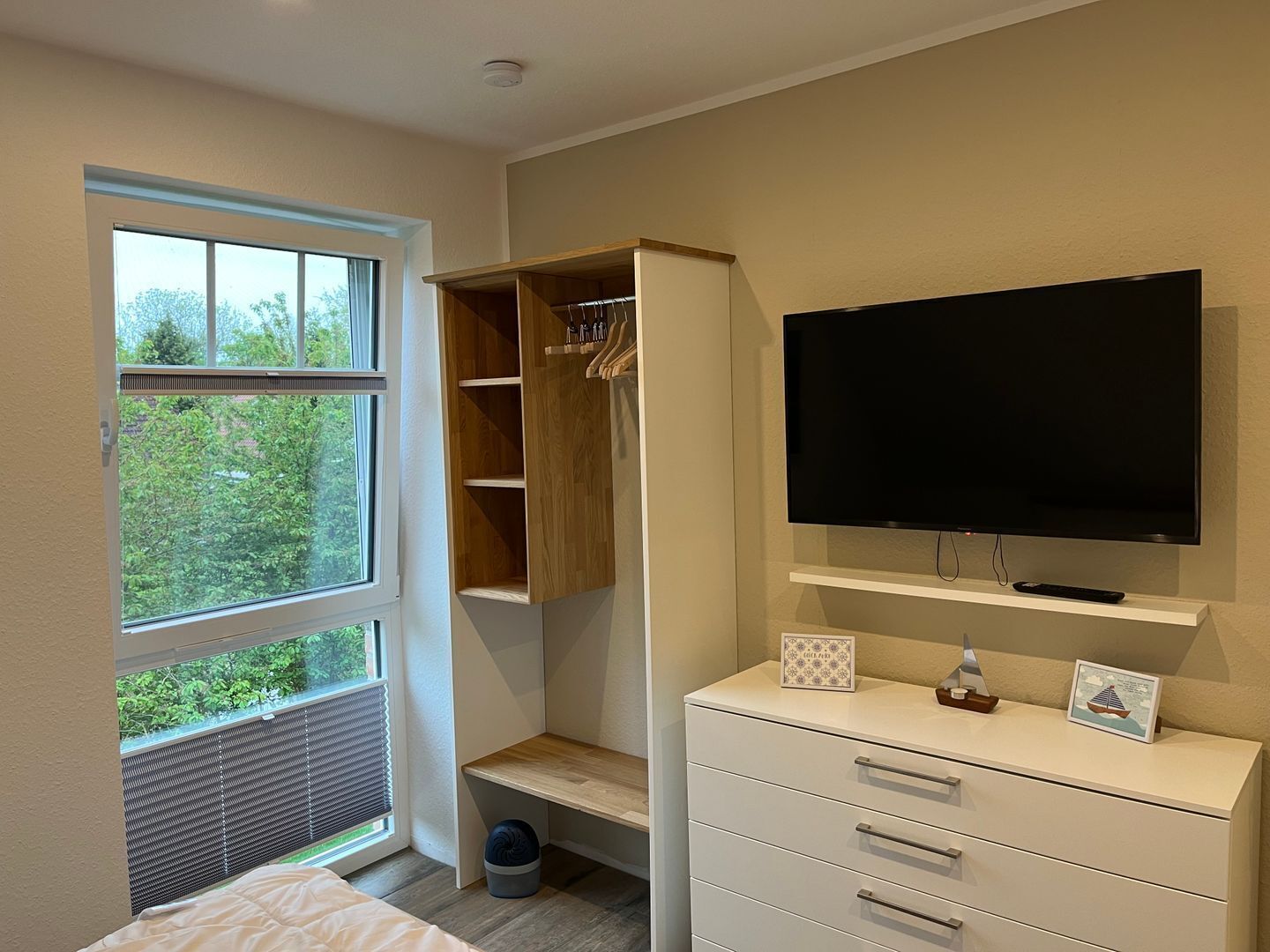Une chambre à coucher avec un lit, une armoire, une télévision et une fenêtre avec des stores.