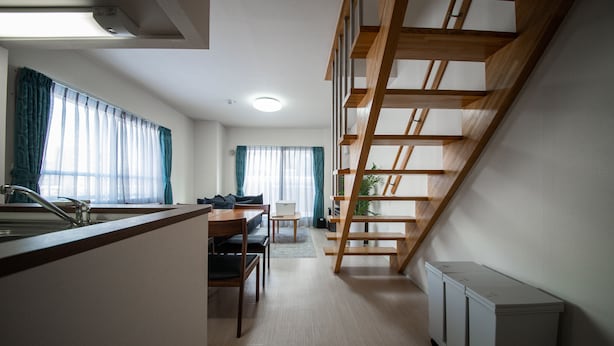 Et moderne køkken med træbordplade, et spiseområde med bord og stole samt en trappe til et niveau oppe.