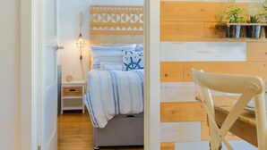 A bedroom with a bed, bedside table, lamp, and a hanging plant.