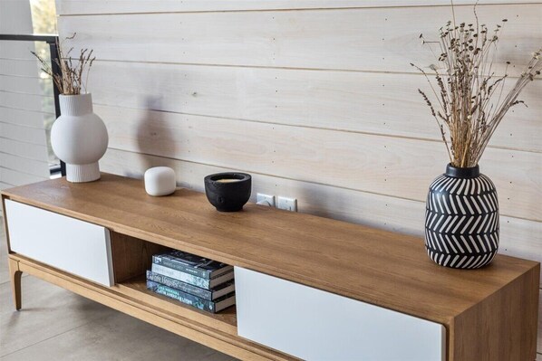 A wooden console table with a white drawer, a black bowl, and two vases with dried plants. - The Penelope: New, Modern Home w/Breathtaking View (Stowe)