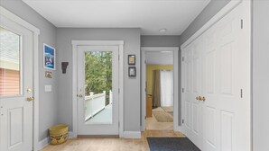 A hallway with a door leading to a balcony, a bench, and a trash bin. - Gorgeous 3 bedroom in popular Stowe location. (Stowe)
