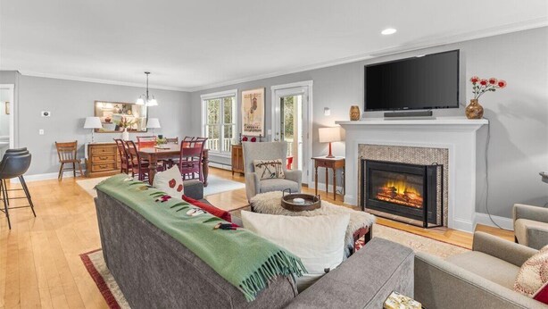 A modern living room with a fireplace, a dining area, and a TV. - Gorgeous 3 bedroom in popular Stowe location. (Stowe)