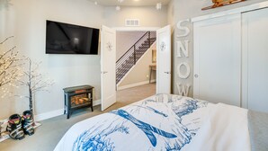 Une chambre à coucher avec un lit, un téléviseur, un escalier et une porte sur laquelle on peut lire le mot « NEIGE ».