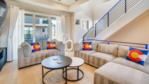 Un salon spacieux comprenant un grand canapé, une table basse et un escalier doté d’une rampe.