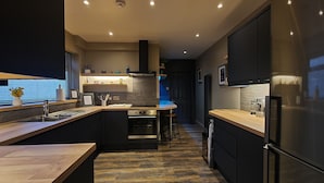 A modern kitchen with a central island, built-in oven, and a refrigerator.