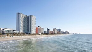 Paesaggio costiero con un hotel sulla spiaggia, edifici alti e cielo sereno.