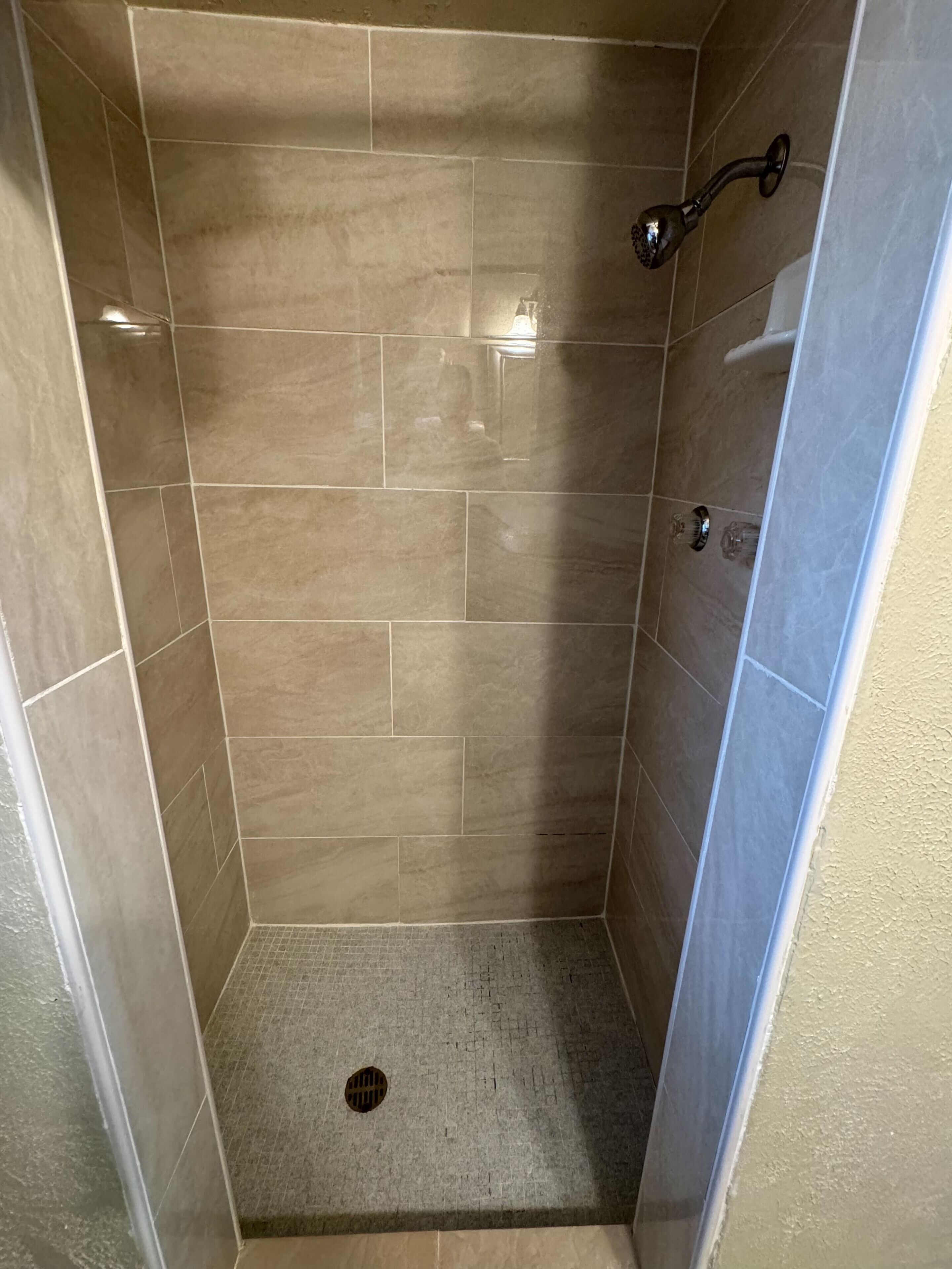 A small, enclosed shower area with tiled walls and a drain.