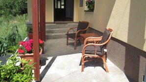 Une terrasse extérieure avec des meubles en osier et des plantes en pot.