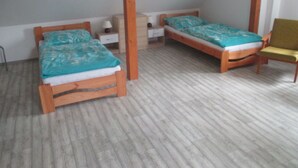 Une pièce comprenant deux lits en bois, une chaise, une table de chevet et une petite table.