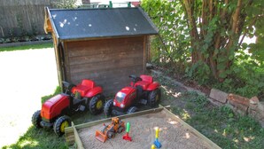 Un abri en bois devant lequel sont garés deux petits tracteurs rouges.