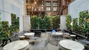 A courtyard with outdoor seating, a brick building with fire escapes, and greenery. - NYC | 5th Ave Premier Studio | Walk to Central Park (New York)
