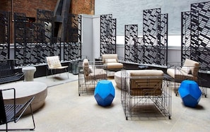 Un espace détente moderne avec des sièges à structure métallique, une table ronde et un élément décoratif bleu aux motifs géométriques.