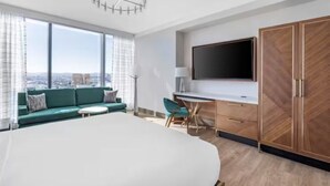A modern hotel room with a large bed, a desk, a sofa, and a TV. - Las Vegas | Group City Retreat | Pool + Gym (Las Vegas)
