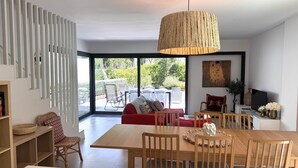 A modern living room with a dining area, large windows, and a view of the outdoors. - VILLA BRASIL  - villa with communal area - Llafranc-Costa Brava (Llafranc)