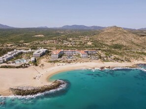 A resort with multiple buildings, a beach, and a large body of water.