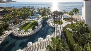 A resort with a large pool, palm trees, and a view of the ocean. - Los Cabos | Elevated Coastal Retreat | Pool + Beach (Cabo del Sol)