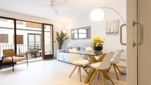 A modern living room with a glass dining table, white chairs, a sofa, and a large window. - CAPDEVILA 9 (Llafranc)