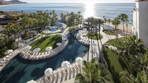 A resort with a large pool, palm trees, and a view of the ocean.