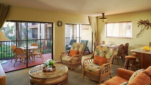 A spacious living area with wicker furniture, a dining table, and a balcony with a view. - Marco Island | Family Beach Getaway | Pool + Beach | 2BR (Marco Island)