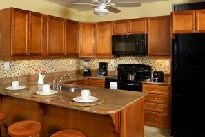 Una cocina con armarios de madera, un refrigerador negro, un microondas y una estufa.