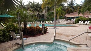 A hot tub surrounded by lounge chairs and palm trees. - Marco Island | Family Beach Getaway | Pool + Beach | 2BR (Marco Island)