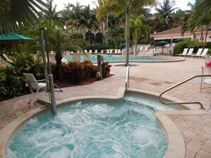 Un jacuzzi rodeado de sillas de descanso y palmeras.